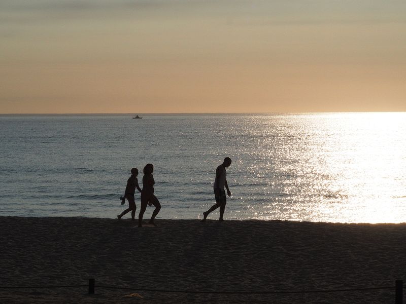 People walk on the beach at sunset